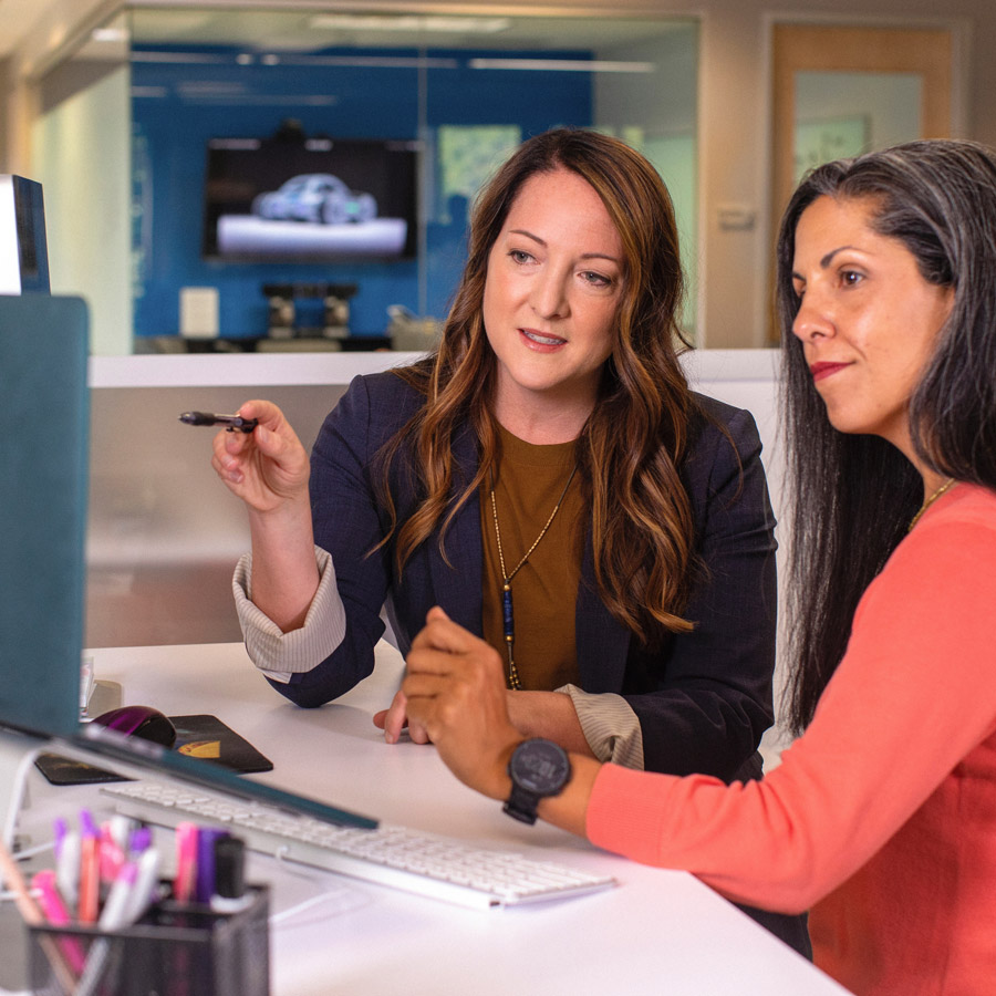 Two women working an a desk in an office setting.