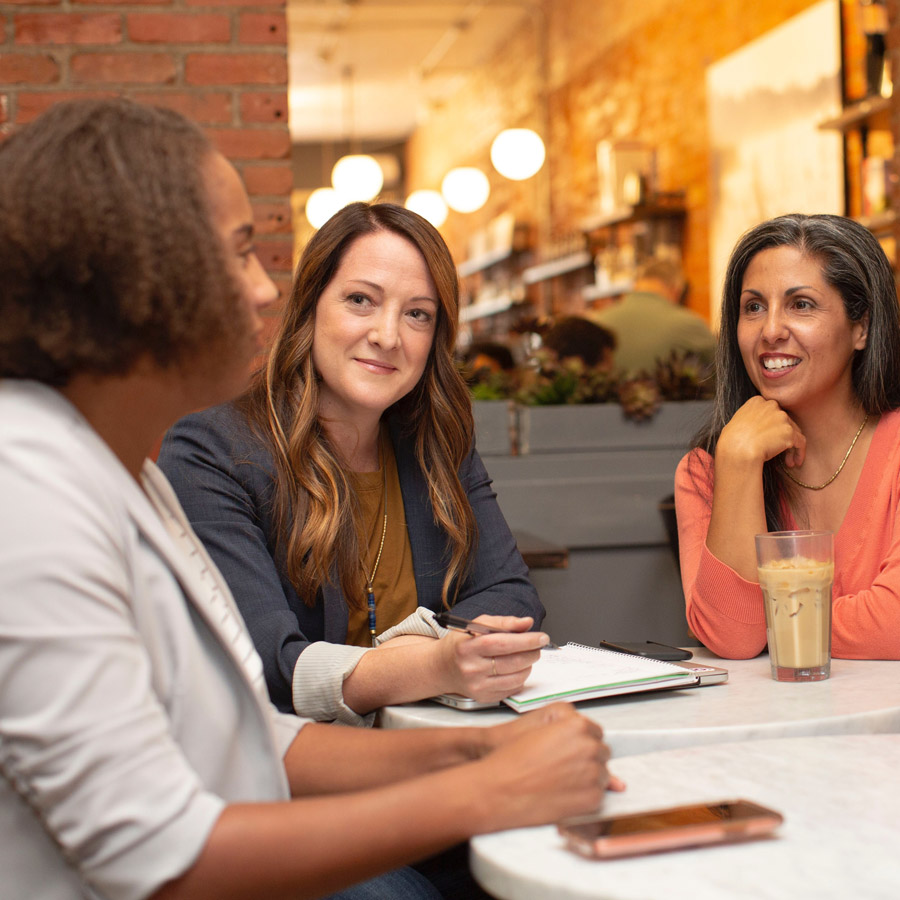 People sitting having a coffee and a woman taking notes.