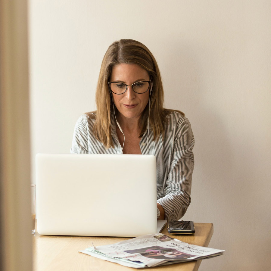 A woman working at a desk with earphones in.